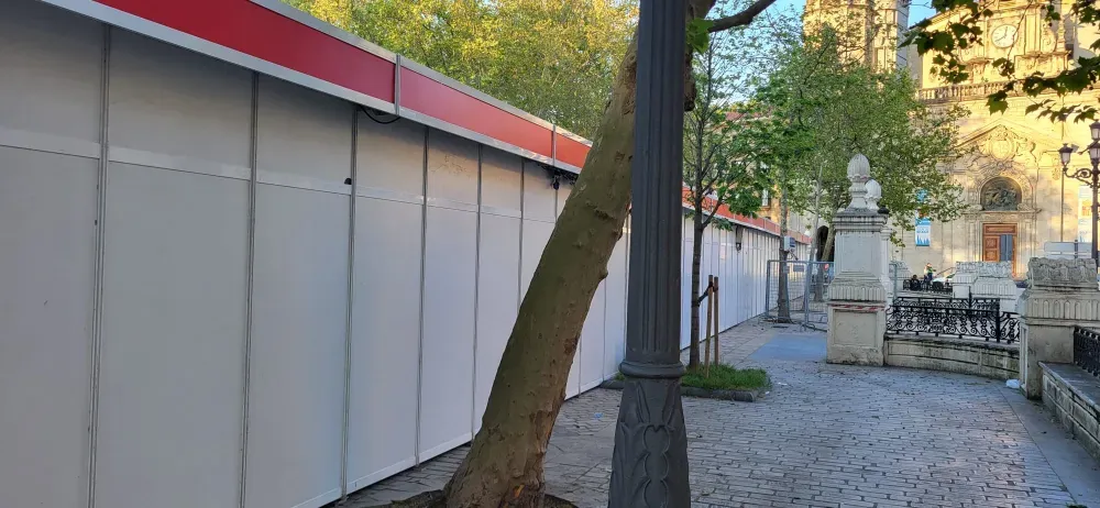 Un sendero arbolado junto a un edificio blanco con techo rojo conduce a una puerta y a coches aparcados.