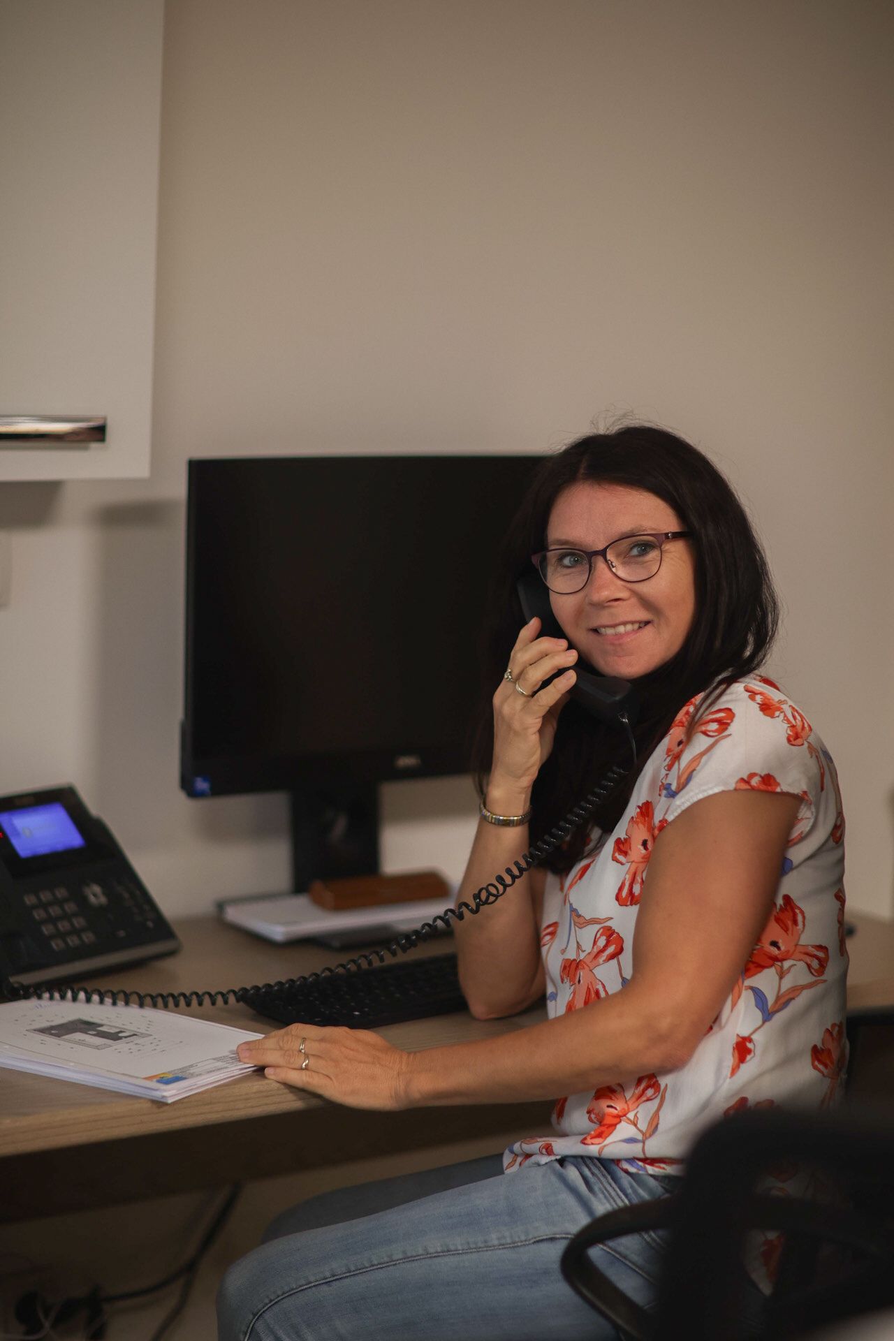 Eine Frau sitzt an einem Schreibtisch und telefoniert.