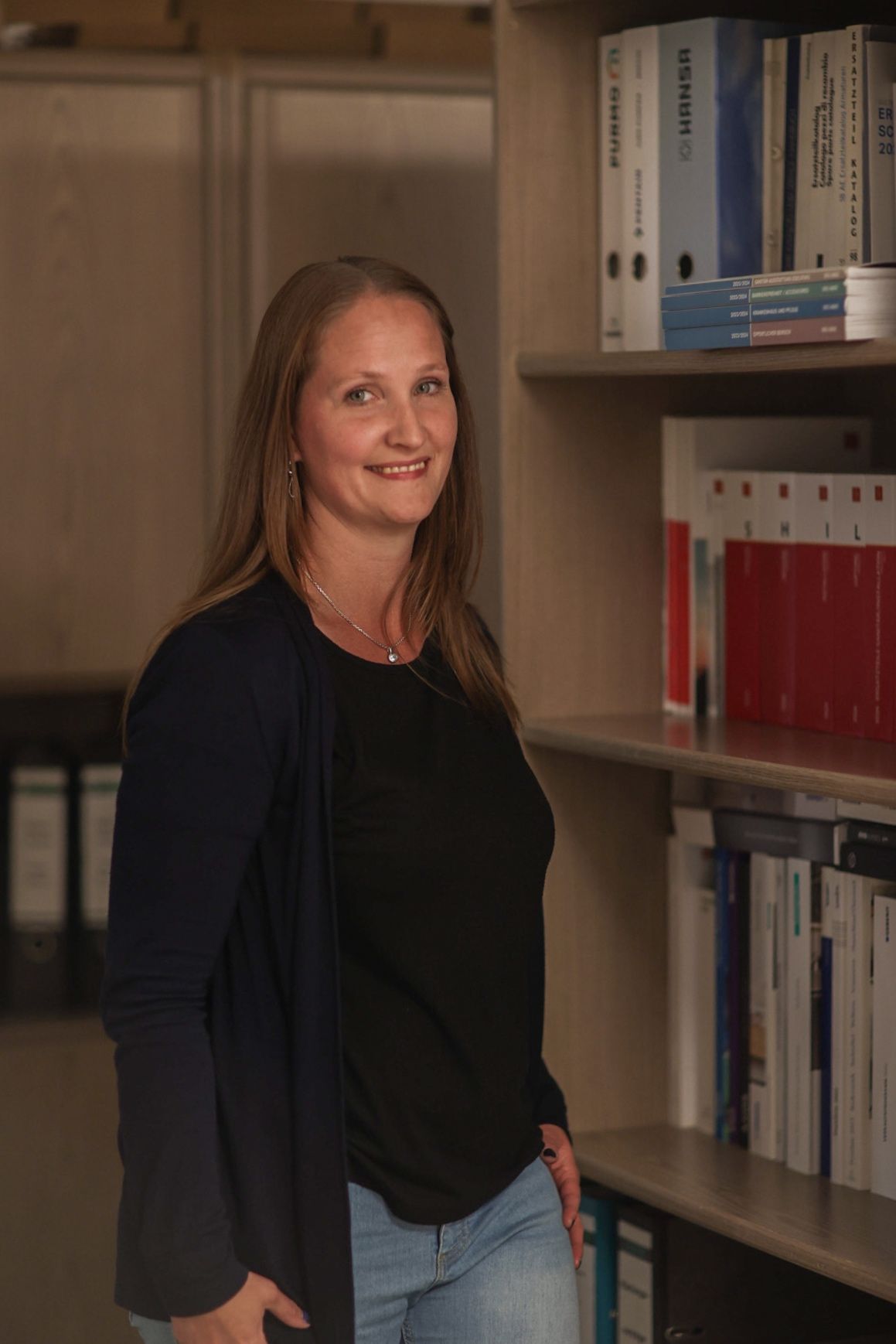 Eine Frau steht vor einem Bücherregal in einer Bibliothek.