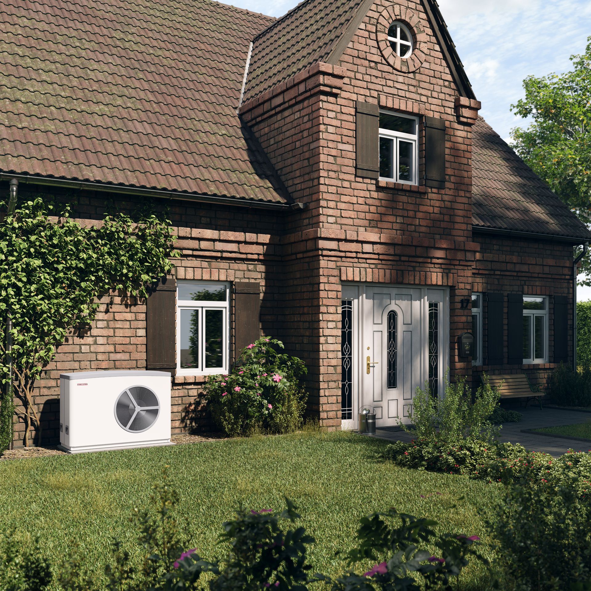 Backsteinhaus mit Wärmepumpe auf dem Rasen; grünes Gras und Büsche mit dunkelbraunen Fensterläden.