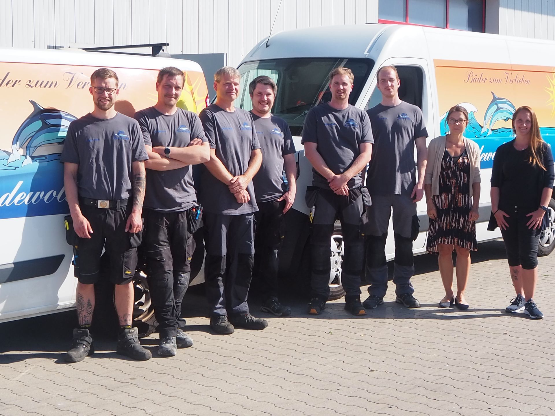 Eine Gruppe von Menschen steht vor einem Lieferwagen mit Delfinen darauf