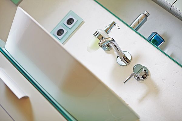 Ein Waschbecken mit Seifenspender und Spiegel