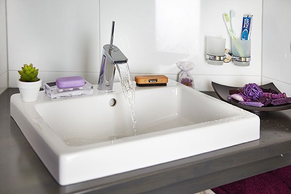 Ein Waschbecken im Badezimmer, aus dessen Wasserhahn Wasser läuft.