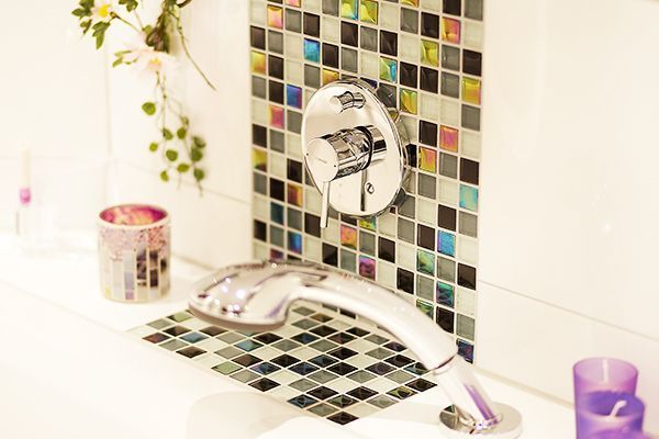 Ein Badezimmer mit einem Wasserhahn und einer Kerze auf der Ablage.