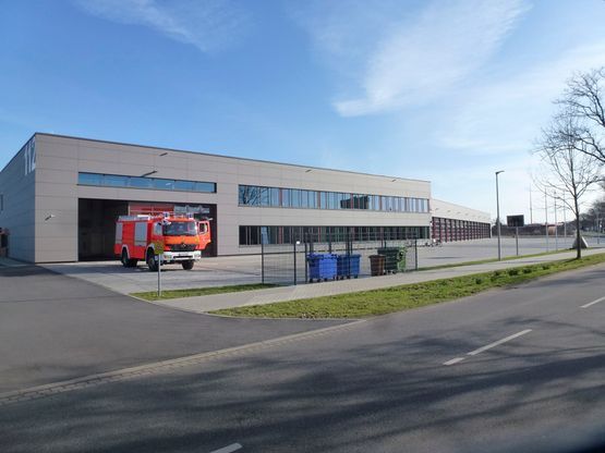 Ein rotes Feuerwehrauto parkt vor einem großen Gebäude.