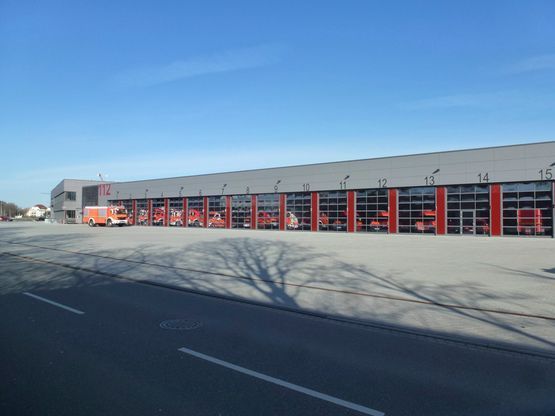 Ein großes Gebäude, vor dem viele Feuerwehrautos geparkt sind.