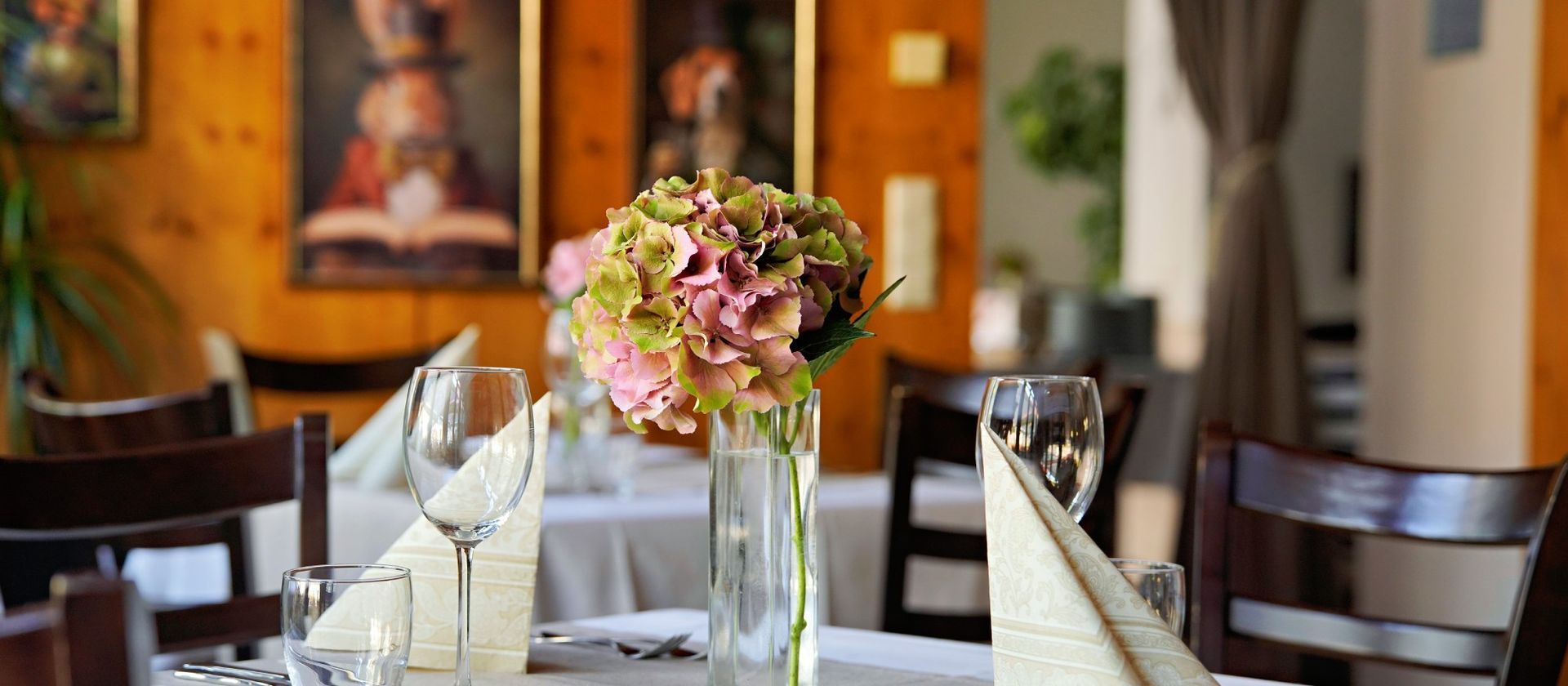 Gedeckter Restauranttisch mit einem Blumenarrangement in einer Vase.