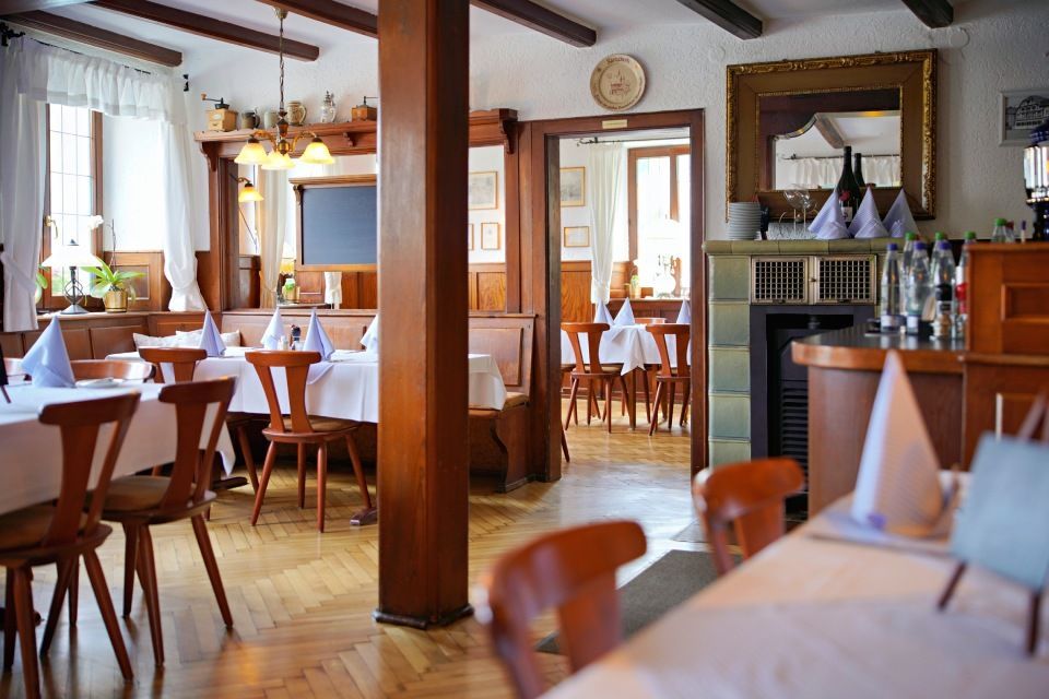 Restaurant-Innenraum mit Holztischen, Stühlen und Balken; Tische mit weißer Tischwäsche, Servietten und Dekor gedeckt.