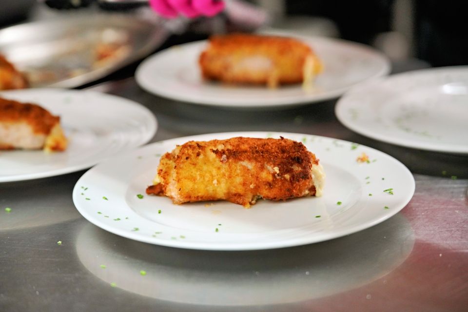 Angerichtetes, paniertes Essen auf weißen Tellern, wahrscheinlich in einer Küche.