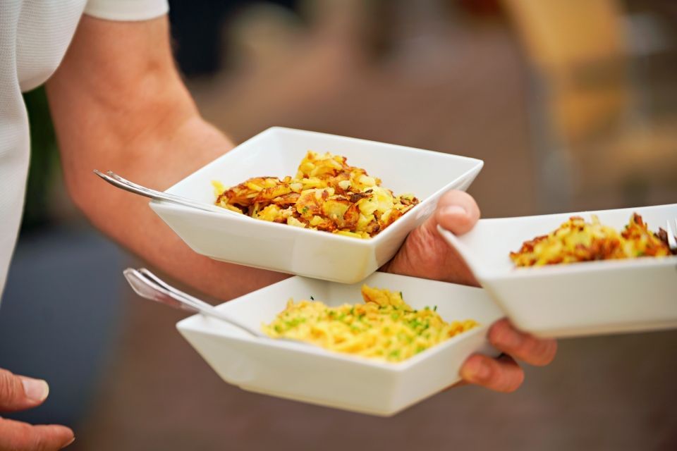 Person hält drei weiße quadratische Schüsseln mit verschiedenen Lebensmitteln, jeweils mit einem Löffel.