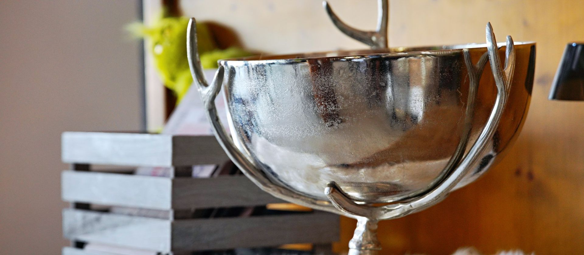 Silberne Trophäe mit geweihartigen Griffen auf einer Holzoberfläche.