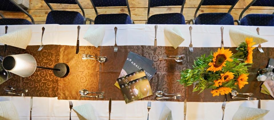 Tischgedeck mit Sonnenblumen, Speisekarten und Besteck, von oben gesehen, mit Stühlen im Hintergrund.