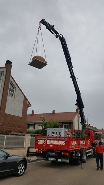Una grúa está levantando un objeto grande desde la parte trasera de un camión.