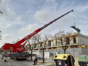Una gran grúa roja está sentada en la parte superior de un edificio.