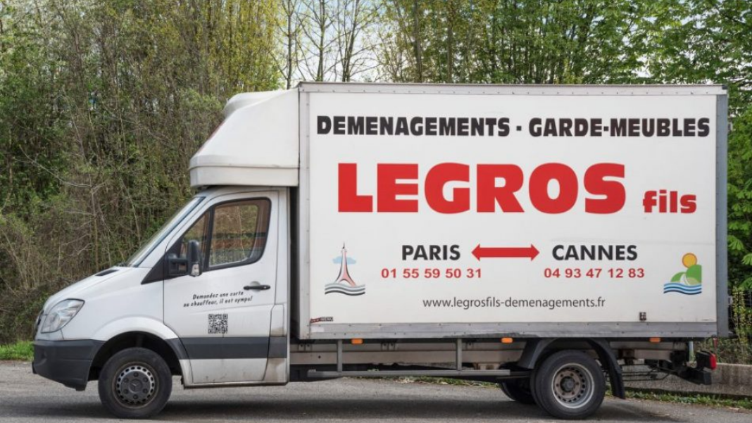 Camion de déménagement blanc avec une pancarte rouge « LEGROS fils »