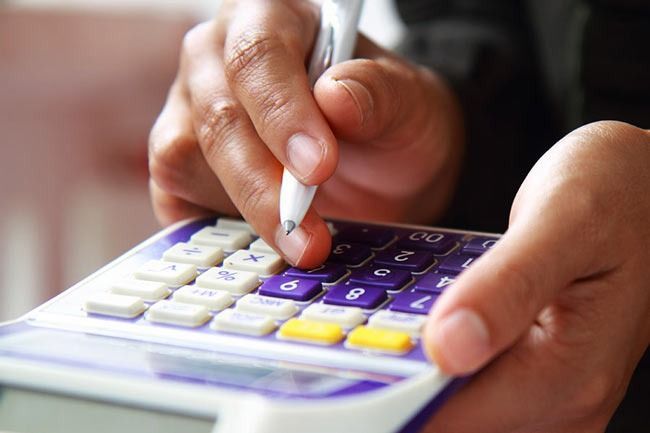 Des mains appuient sur les touches d'une calculatrice.