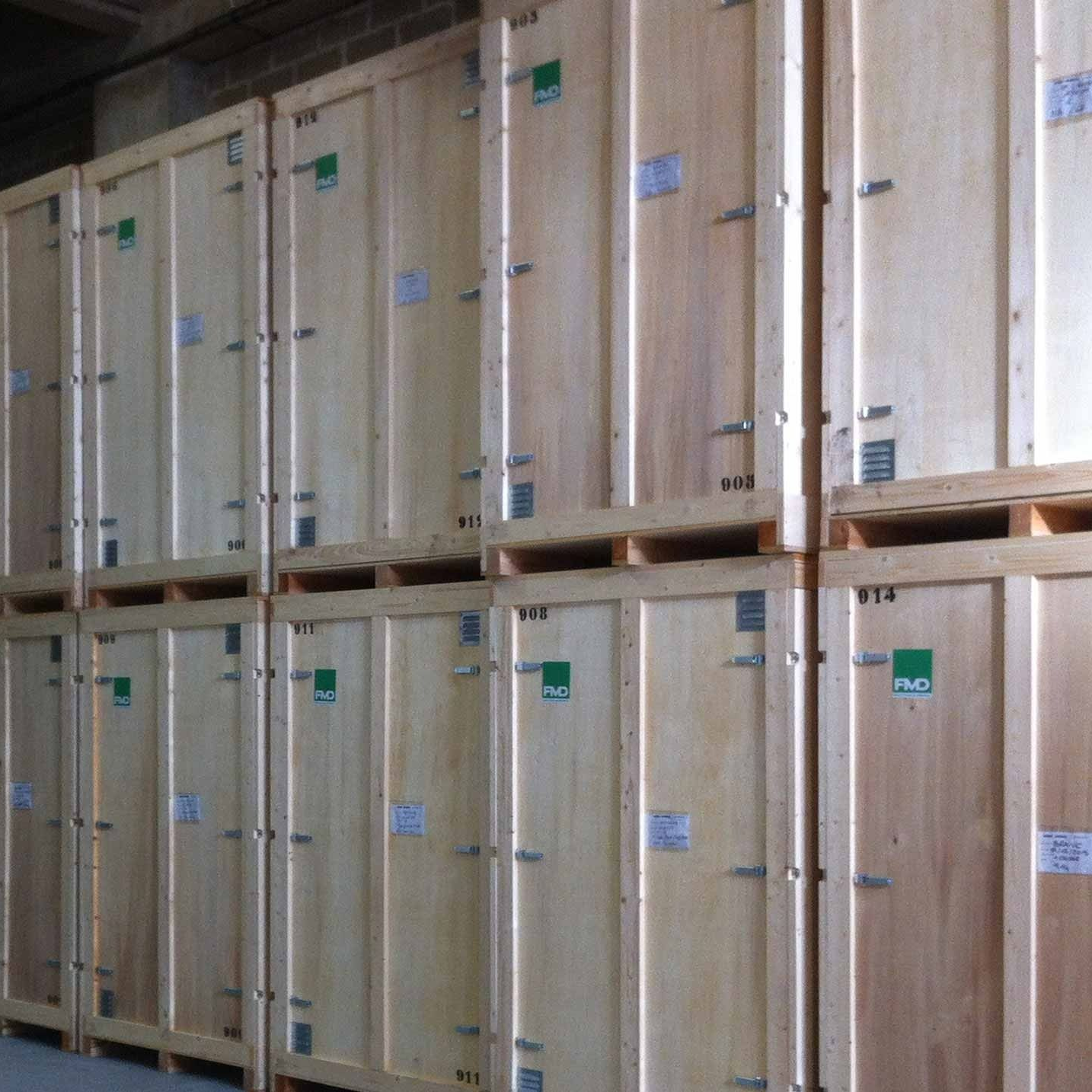 Des caisses d'expédition en bois empilées dans un entrepôt, disposées en rangées sur des étagères.