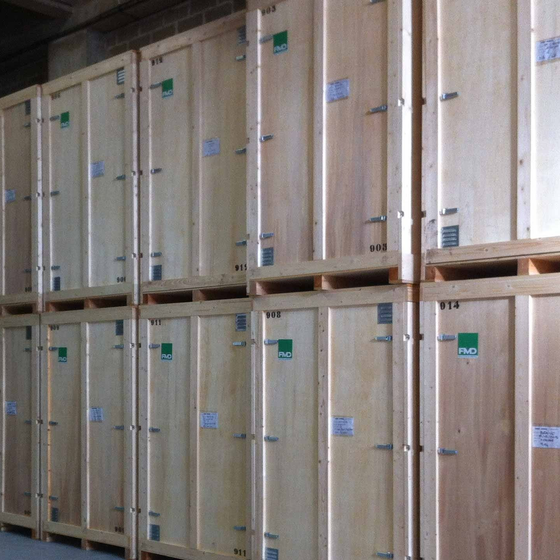 Des caisses d'expédition en bois empilées dans un entrepôt, disposées en rangées sur des étagères.