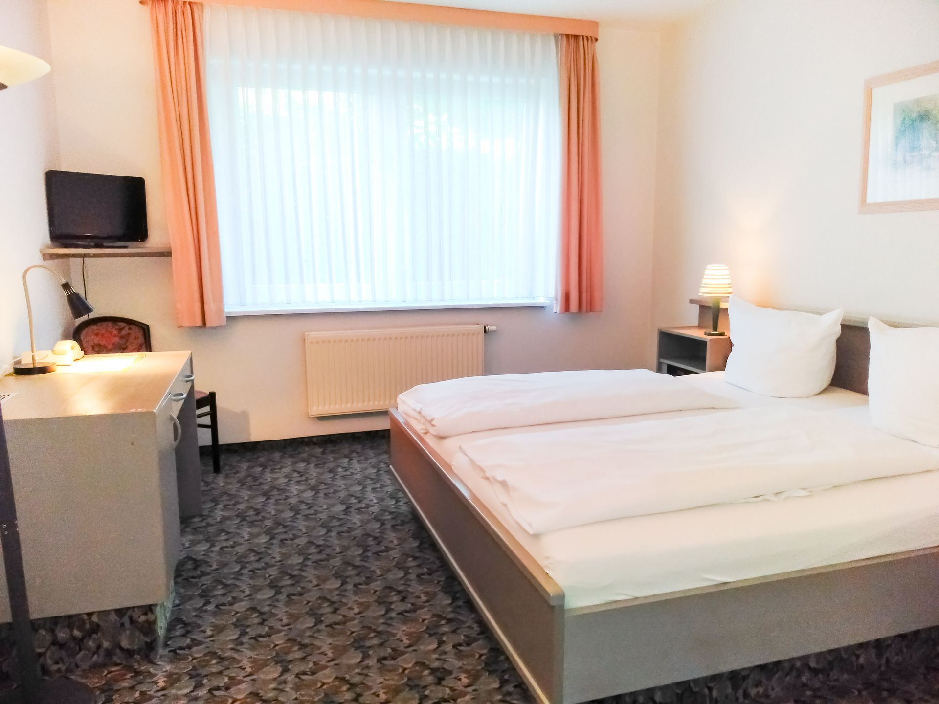 Ein Hotelzimmer mit zwei Betten, einem Schreibtisch und einem Fernseher