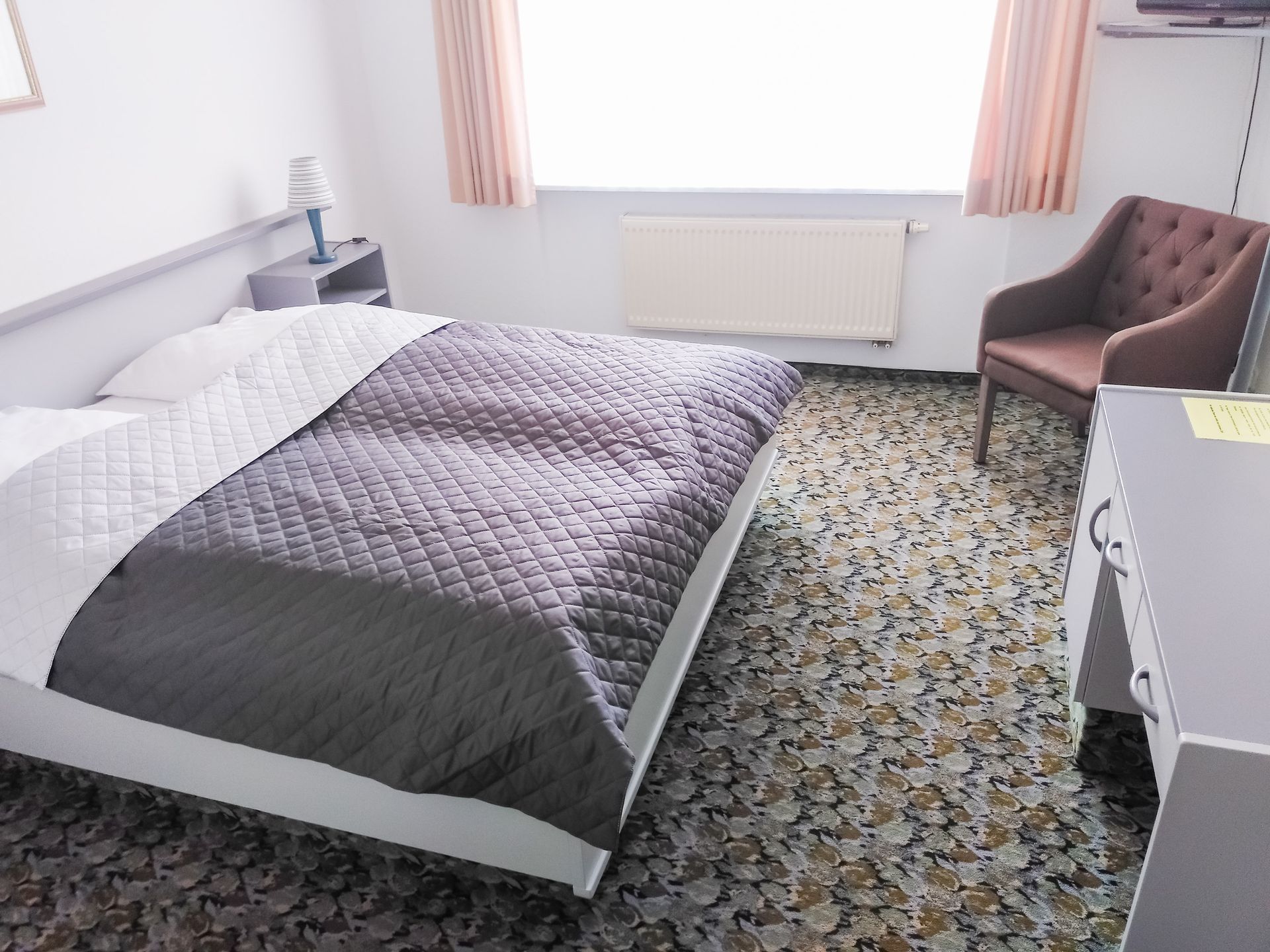 Ein Hotelzimmer mit einem großen Bett und einem Stuhl