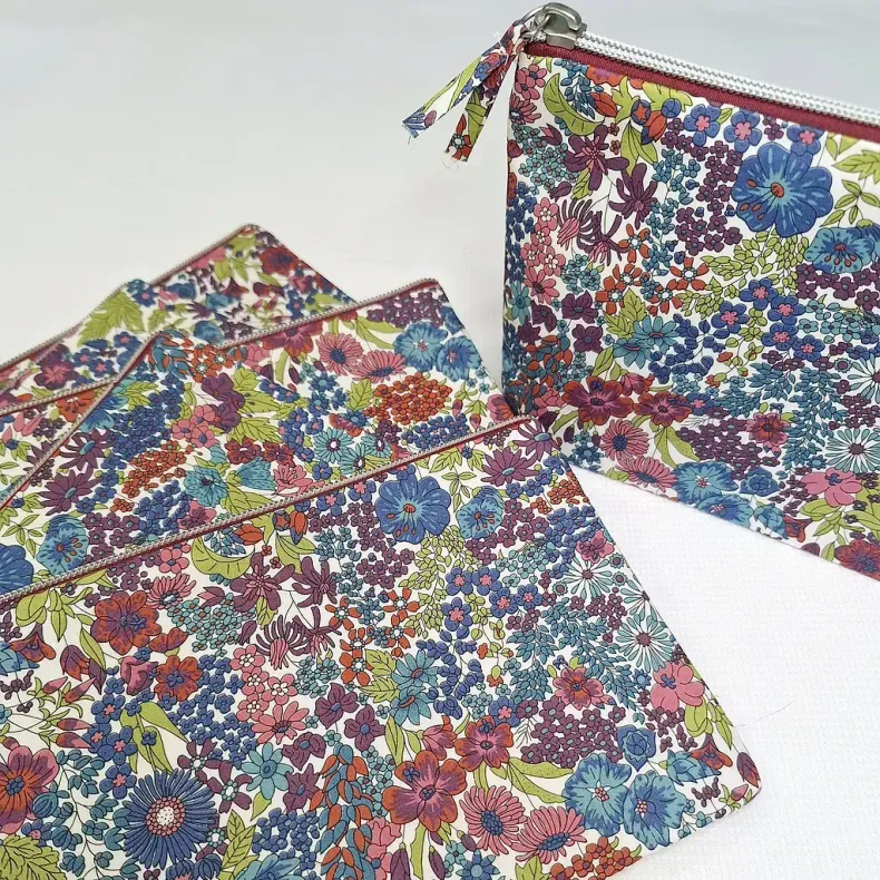 Un montón de bolsos con flores de colores colocados uno encima del otro.