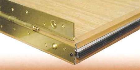 Un primer plano de una mesa de madera con bisagras de latón.