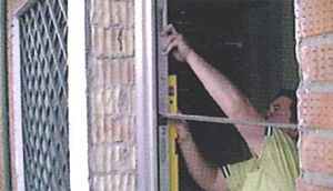 Un hombre está usando un nivel para medir el marco de una ventana.