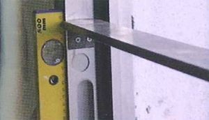 Un nivel amarillo está junto a un estante en una pared.