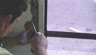 Un hombre está cortando un trozo de metal con un par de tijeras.