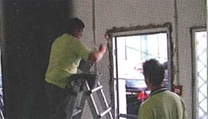 Un hombre está sentado en una escalera trabajando en una puerta.