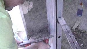 Un hombre está cortando un trozo de madera con un par de tijeras.