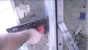 Una persona está usando una espátula para esparcir hormigón en una pared.