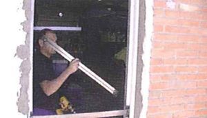 Un hombre está instalando un marco de ventana en una pared de ladrillos.