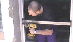 Un hombre está usando un taladro para instalar una ventana.