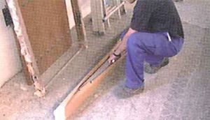 Un hombre está arrodillado en el suelo sosteniendo un trozo de madera.