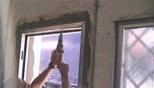 Un hombre está usando un taladro para instalar un marco de ventana.