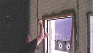 Un hombre está instalando una ventana en una habitación.