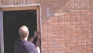 Un hombre está parado frente a una pared de ladrillos.