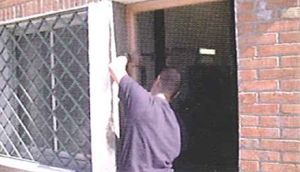 Un hombre está limpiando una ventana con un paño frente a un edificio de ladrillos.