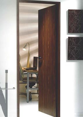 Una puerta de madera se abre a una habitación con un escritorio y una silla.