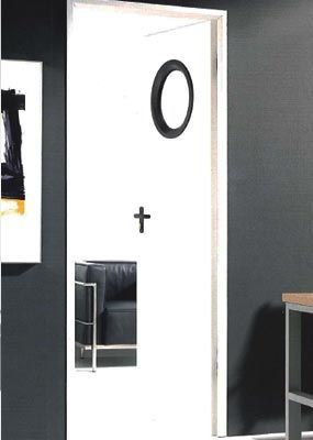 Una puerta blanca con un círculo negro y una cruz sobre ella.