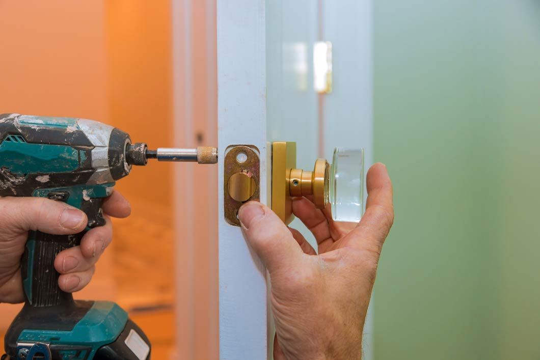 Una persona está instalando una manija de puerta con un taladro.