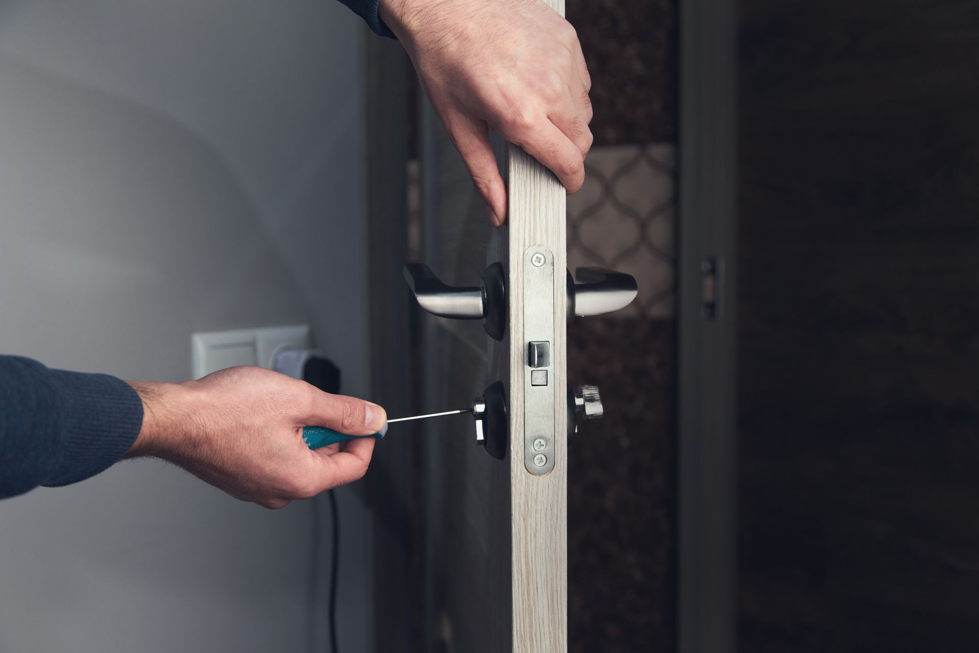 Un hombre está arreglando una puerta con un destornillador.