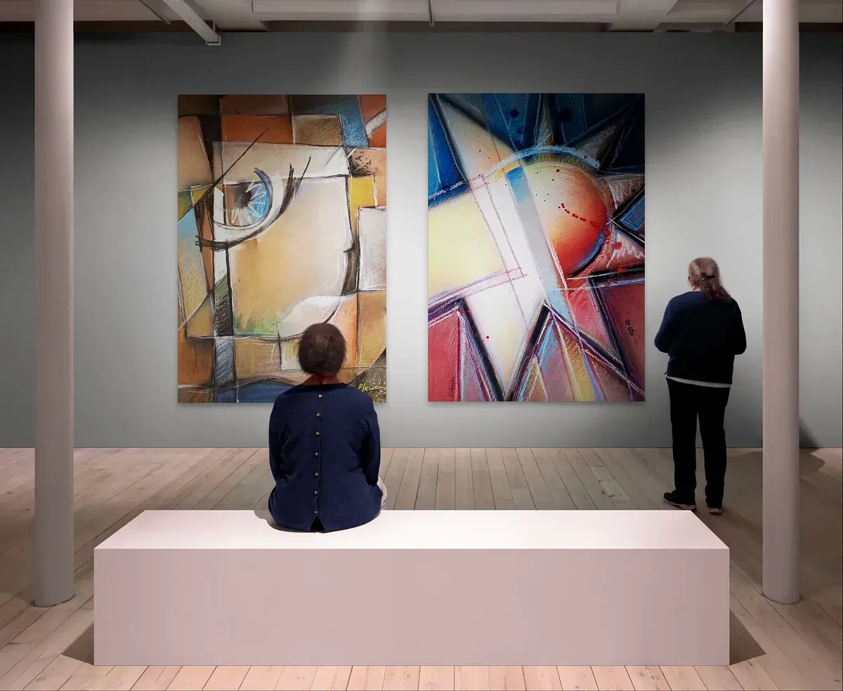 Una mujer se sienta en un banco en un museo mirando pinturas.
