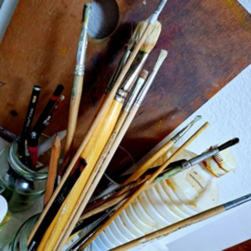 Mujer de pelo oscuro, sonriente, con maquillaje de ojos intenso, apoyada contra una chaqueta de cuero oscura.