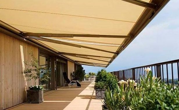 Toldo retráctil beige sobre un balcón con plantas, con vista.