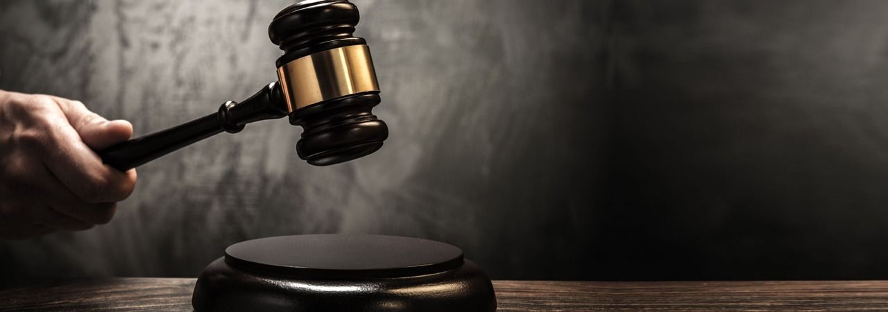 El mazo del juez golpea un bloque de sonido en una oscura escena de la sala del tribunal.