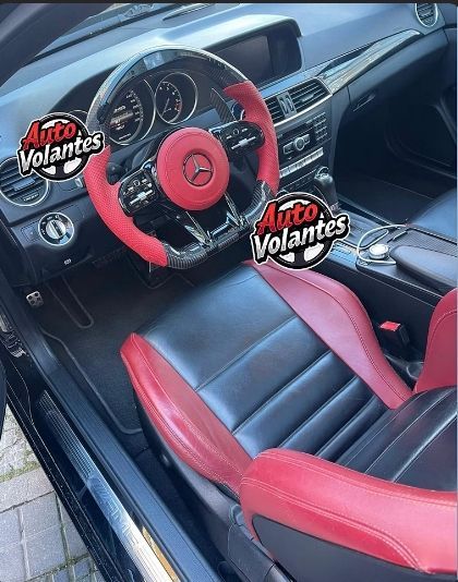 Interior de Mercedes negro con detalles rojos en el volante y los asientos.