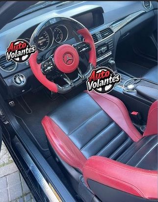 Interior de Mercedes negro con detalles rojos en el volante y los asientos.