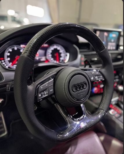Volante de fibra de carbono de un Audi, con detalles en rojo en el tablero.